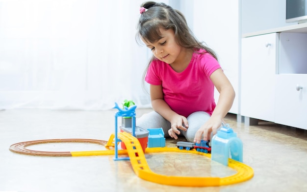 Baby-Spiel. Kleines cleveres kaukasisches Kind, das bunte Spielzeugeisenbahn und Zug für die frühe Entwicklung spielt. Freizeit für Kinder im Vorschulalter.