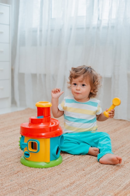 Baby spielt auf dem Boden im Raum in pädagogischem Plastikspielzeug.