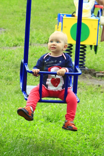 Baby spielt auf der Schaukel auf dem Spielplatz