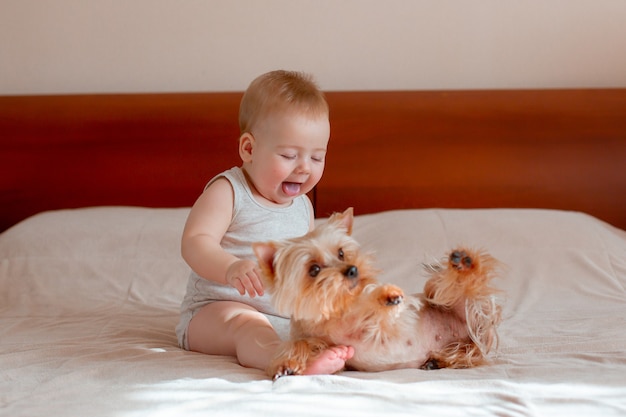 Baby spielt im Schlafzimmer auf dem Bett mit seinem Hund