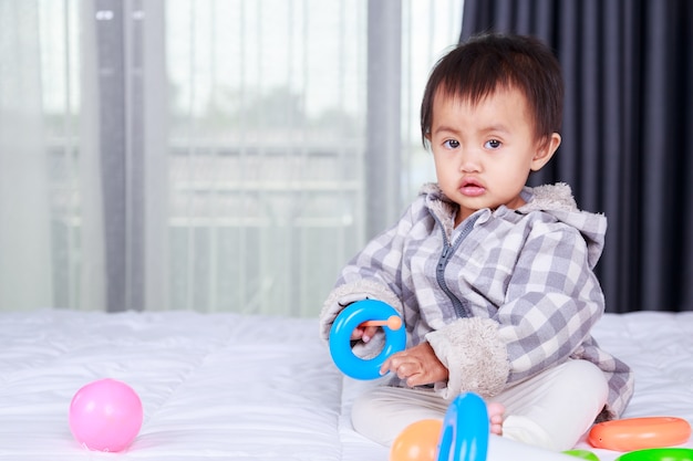 Baby spielt mit Spielzeug auf dem Bett