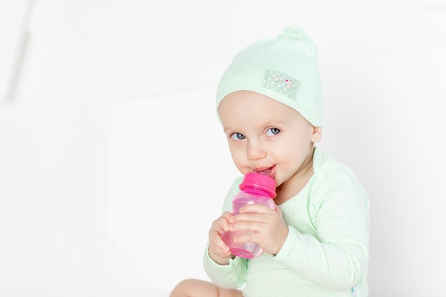 Baby spielt mit spielzeug im kinderzimmer zu hause in einem grünen body, dem konzept der entwicklung und freizeitgestaltung von kleinkindern