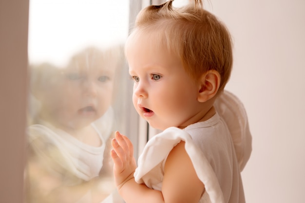 Baby steht auf der Fensterbank und schaut aus dem Fenster