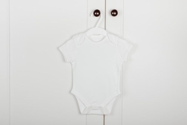 Baby süßer weißer Body auf einem Kleiderbügel Weißer Hintergrund Babykleidung Mock-up für Design