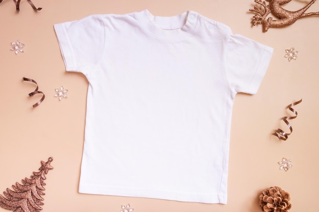Baby-T-Shirt-Modell für Logo-Text oder Design auf beigem Hintergrund mit Draufsicht der Winterdekoration