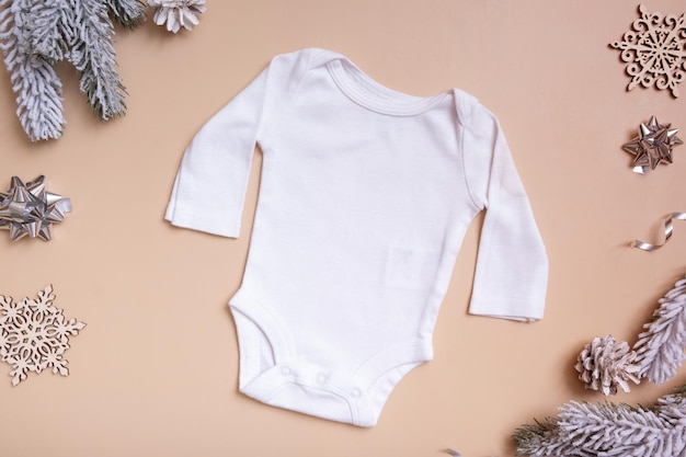 Baby-T-Shirt-Modell für Logo, Text oder Design auf beigem Hintergrund mit Draufsicht der Winterdekoration