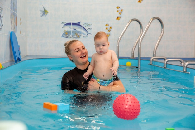 Baby trainiert, um im Pool mit einem Trainer zu schwimmen