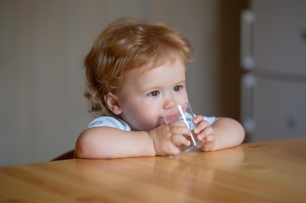 Baby-Trinkglas Wasser Gesunde Ernährung für Kinder Porträt des kleinen Babys, das in häuslicher Umgebung trinkt