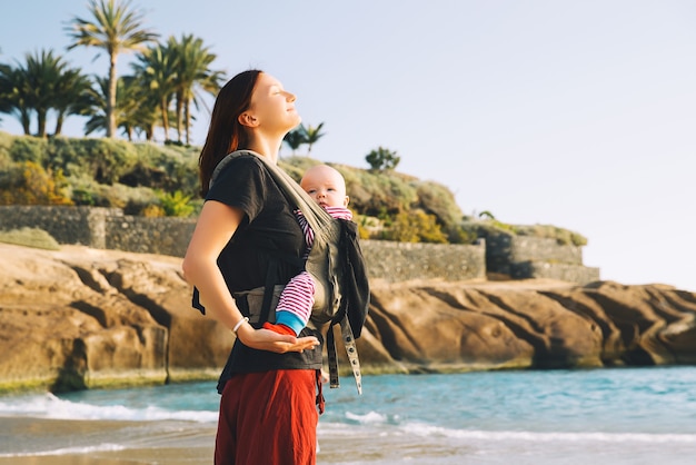 Baby und Mutter auf dem Meer am Sommertag Glückliche Familie, die draußen auf der Natur spazieren geht