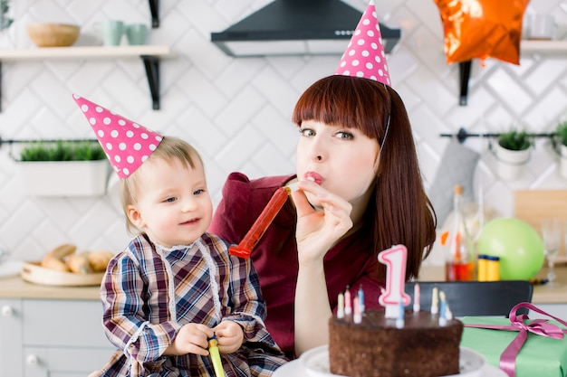 Baby und Mutter blasen in Partyhorn