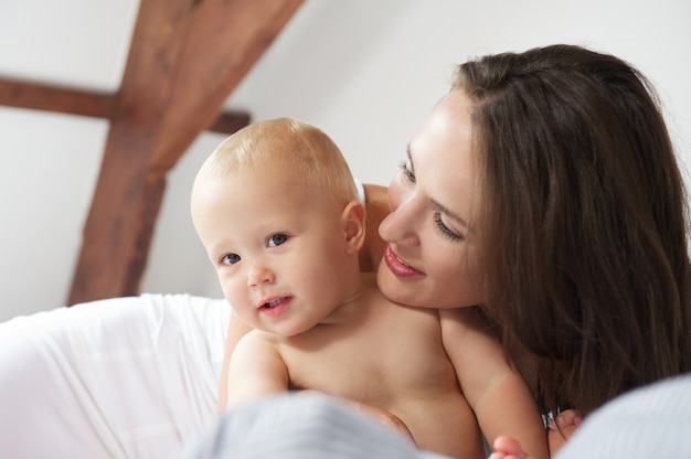 Baby und Mutter, die auf Bett lächeln