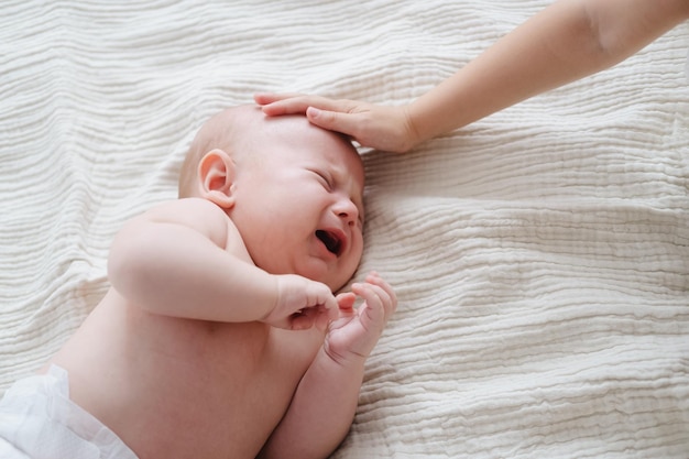 Foto baby weint und geschwister streicheln den kopf