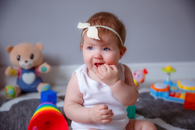 Baby zu Hause sitzt auf dem Boden und spielt mit Spielzeug