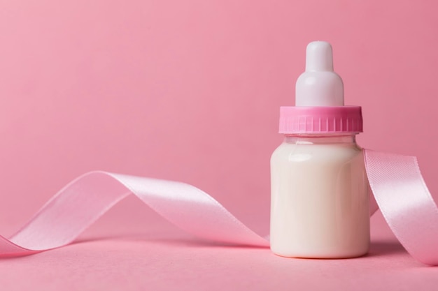 Babyflasche auf pastellrosa Hintergrund Neue Babyankunft