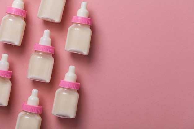 Babyflaschen mit Milch auf pastellrosa Hintergrund