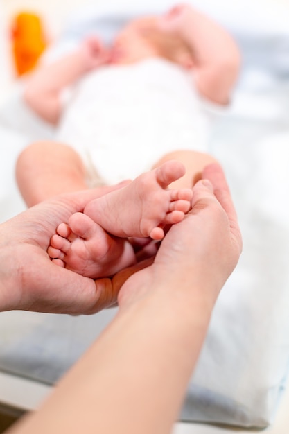 Babyfüße in Mutterhänden. Winzige neugeborene Babyfüße auf weiblicher geformter Handnahaufnahme. Mutter und ihr Kind. Glückliches Familienkonzept. Schönes konzeptuelles Bild der Mutterschaft