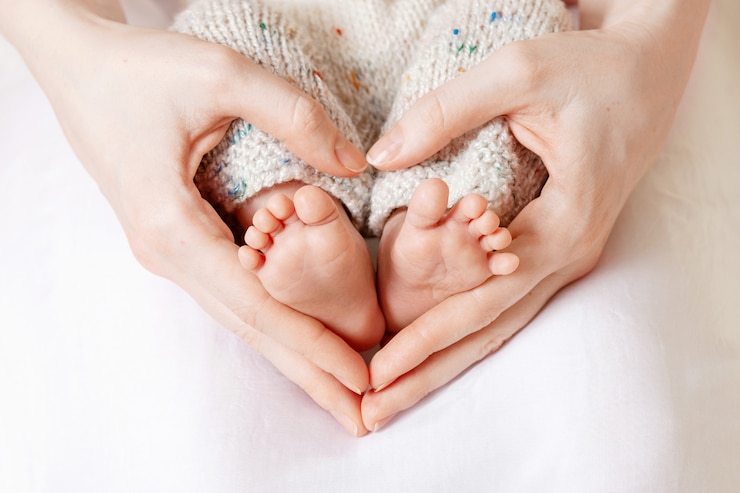 Foto babyfüße in mutterhänden. winzige neugeborenenbabys füße auf weiblicher herzförmiger handnahaufnahme