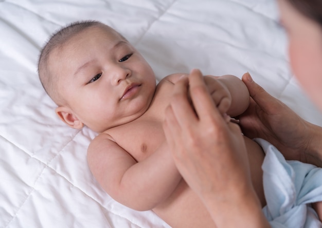 Babyhand, die Finger der Mutter auf Bett hält