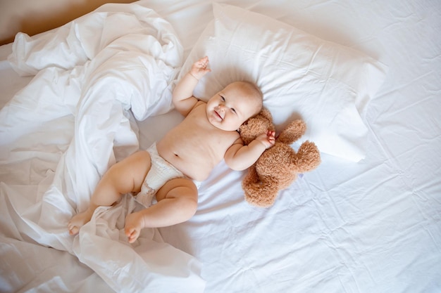 Babyjunge zu Hause im Schlafzimmer, das auf einer Draufsicht des weißen Blattes liegt