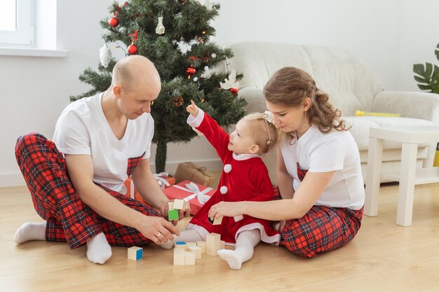 Babykind mit Hörgerät und Cochlea-Implantat, das Spaß mit den Eltern im Weihnachtsraum hat, taub div