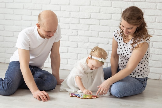Babykind mit Hörgeräten und Cochlea-Implantaten spielt mit Eltern auf dem Boden taub und
