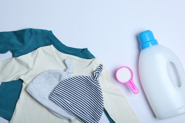 Babykleidung und Waschmittel auf einer farbigen Hintergrundansicht von oben