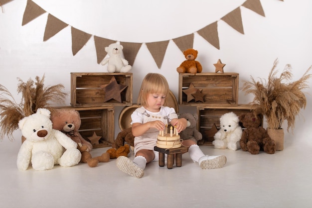 Babymädchen auf einem weißen Hintergrund mit einem Kuchen und Teddybären.