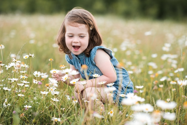 Babymädchen, das mit Blumen spielt, die in der Wiese aufwerfen