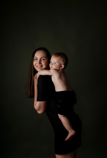 Babymädchen, das sich an Mama Brunette auf einem grünen Hintergrund mit einem Platz für Text festhält