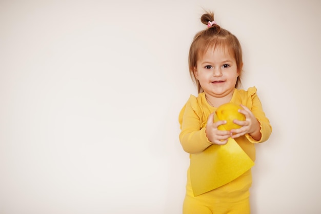 Babymädchen im Gelb mit Zitrone und Karte, lokalisierter Hintergrund.