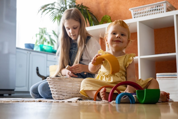 Babymädchen im Kleid, das Regenbogenbogenblockbau baut, der ökologischen hölzernen Spielzeugturm baut