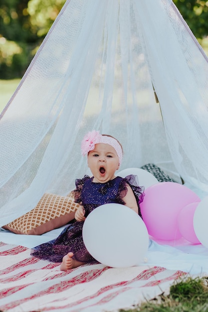 Babymädchen im violetten Kleid, das Spaß im Garten hat