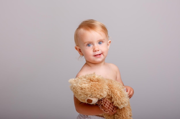 Babymädchen in der Windel, die Teddybären auf weißem Hintergrund hält