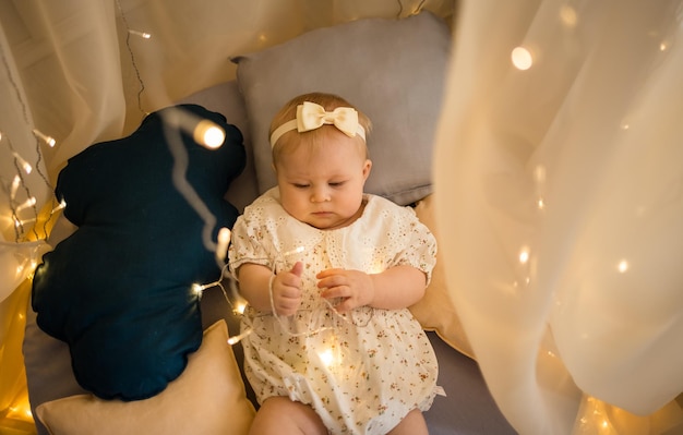 Foto babymädchen liegt im bett auf einer matratze unter einem baldachin und spielt mit einer girlande