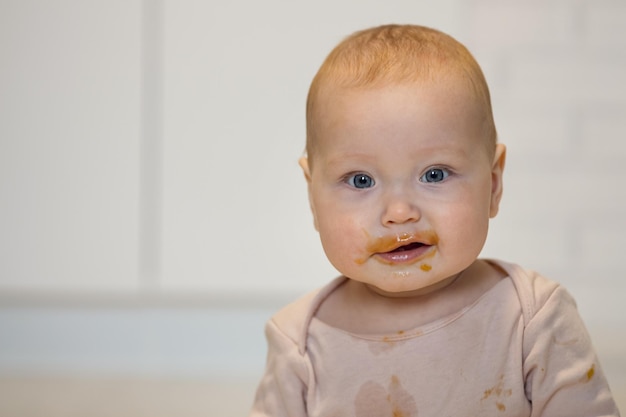 Babymädchen mit aufgeregtem Gesichtsausdruck wird vom Essen schmutzig
