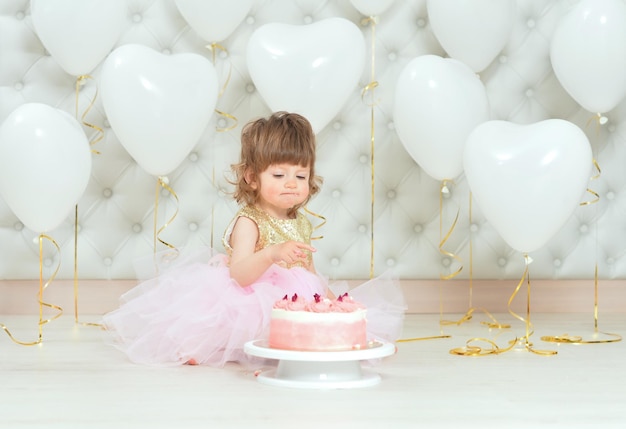 Babymädchen mit Kuchen an ihrem Geburtstag, der zu Hause aufwirft