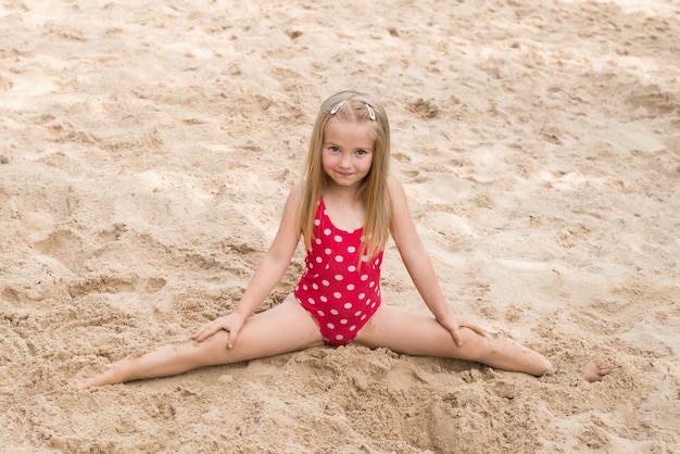 Babymädchen sitzt auf einer Schnur im Sand am Strand