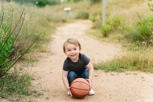 Babymädchen sitzt beim Spielen mit einem Ball im Freien