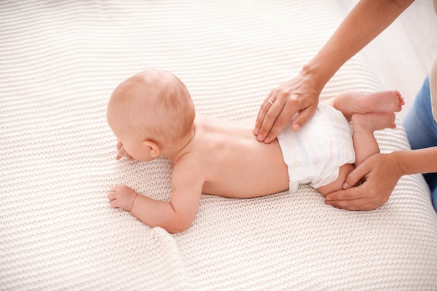 Babymassagebaby, das auf seinem Bauch liegt und versucht zu kriechen