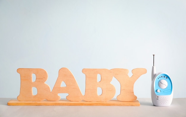 Babyphone und Holzbuchstaben auf Tisch gegen Farbe