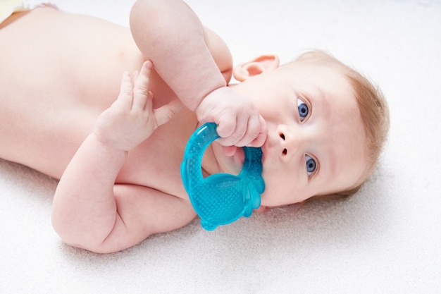 Babys Zähne werden geschnitten. süßes Kind mit blauen Augen knabbert ein Spielzeug.