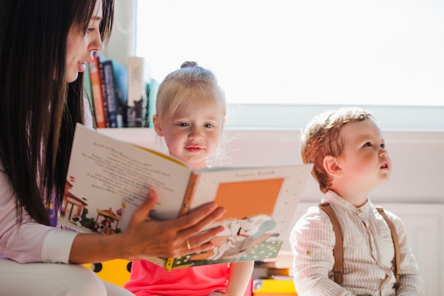 Babysitter zeigt Buch zu Mädchen