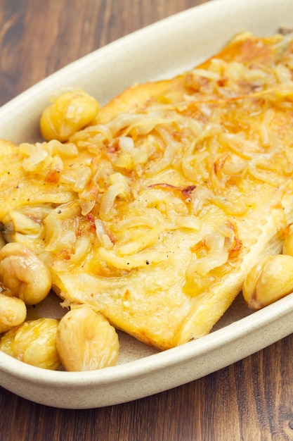 Bacalao con castañas en plato sobre superficie de madera