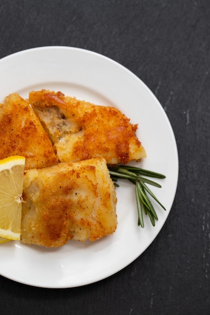 Bacalao frito con limón en plato blanco