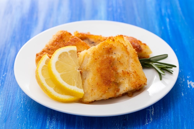 Bacalao frito con limón en plato blanco