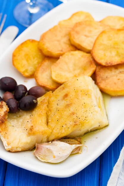 Bacalao frito con patata en un plato blanco