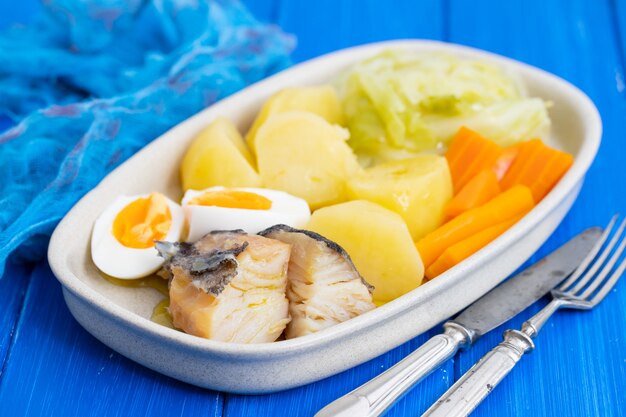 Bacalao con huevo cocido y verduras en el plato