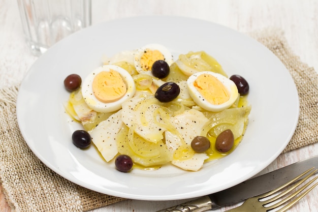 Bacalao con patata, huevo y aceitunas en plato