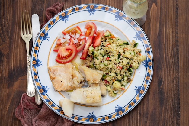 Bacalao con quinoa y ensalada fresca en plato