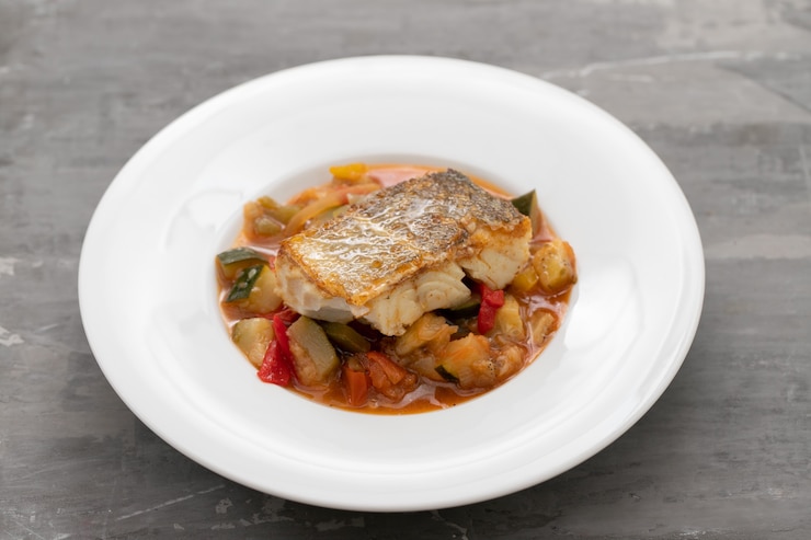 Foto bacalao con verduras en plato blanco